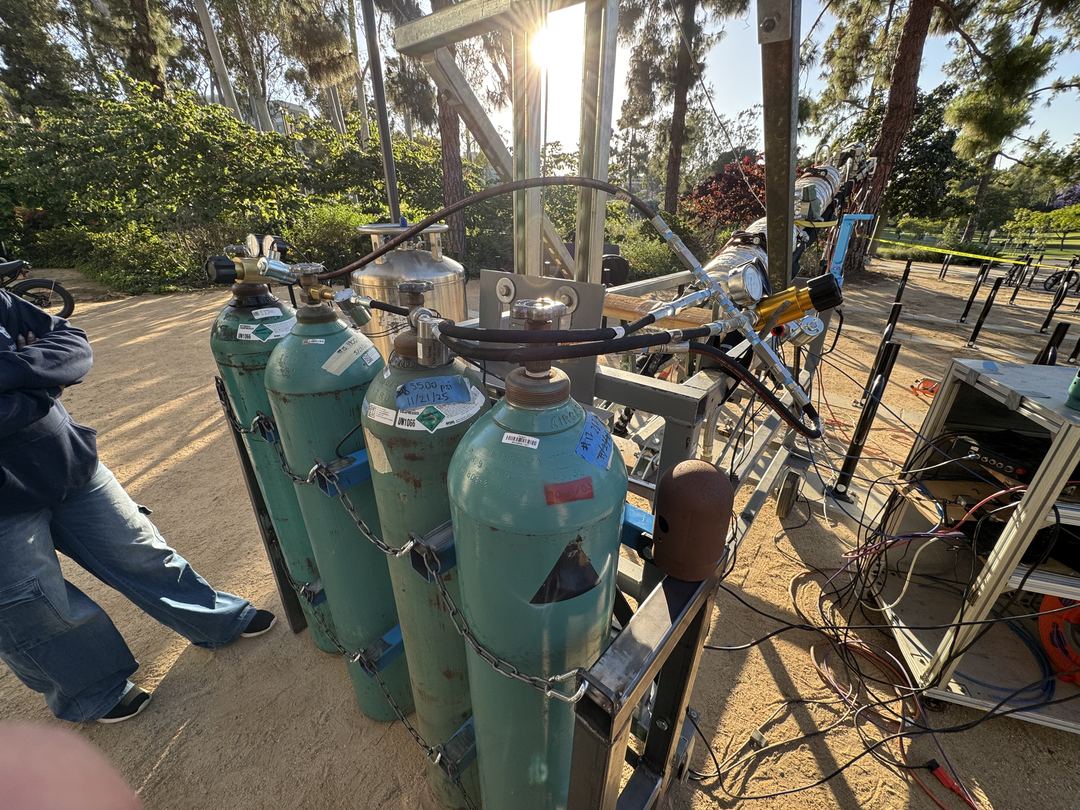 The four K-bottles manifolded together in their frame on the test stand, a braided line running up to the vehicle