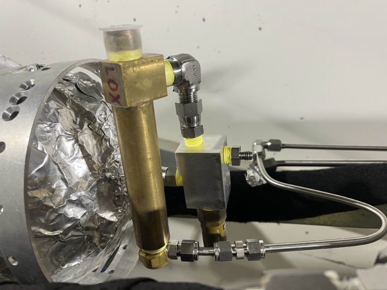 A manifold block installed on the vehicle with fittings running to the foil-wrapped tank