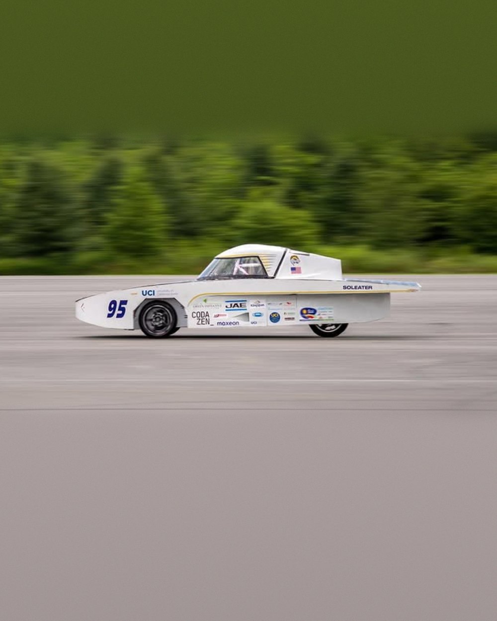 UCI's first solar car, numbered 95 and lettered SOLEATER, running at speed on a track