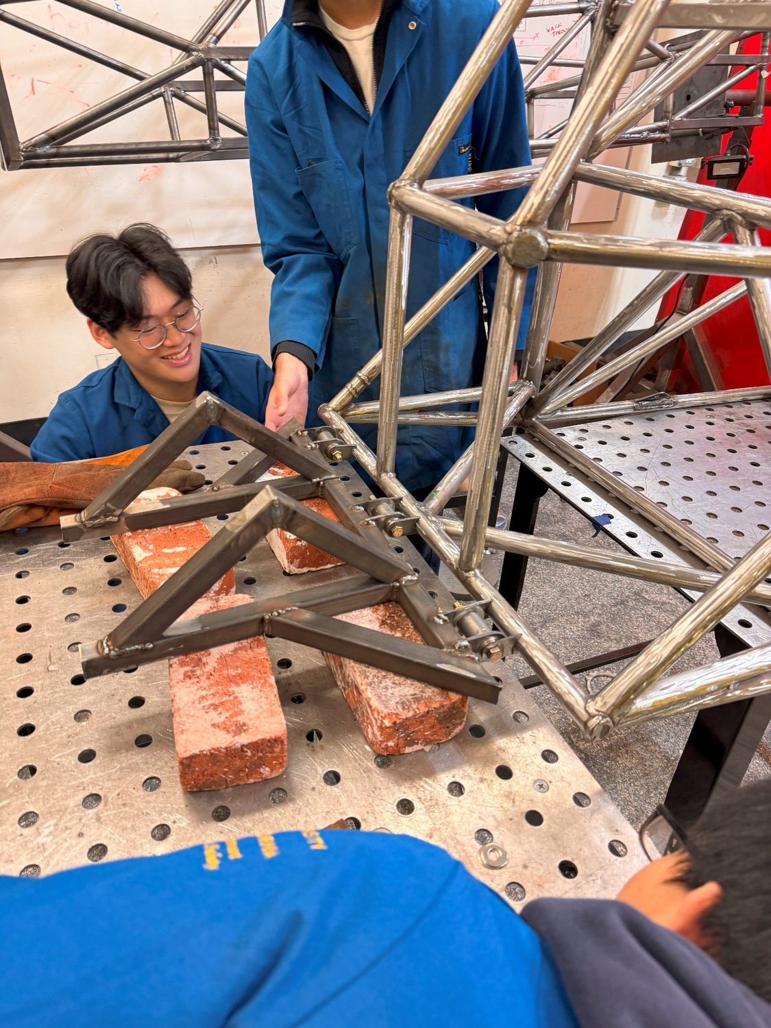 Subteam members checking the trailing-arm weld on the chassis